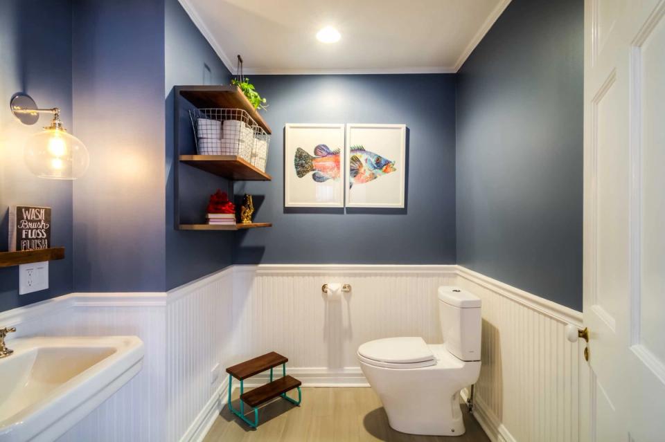 Transitional bathroom with navy accent wall, white shiplap wainscoting, and brass fixtures creating sophisticated contrast
