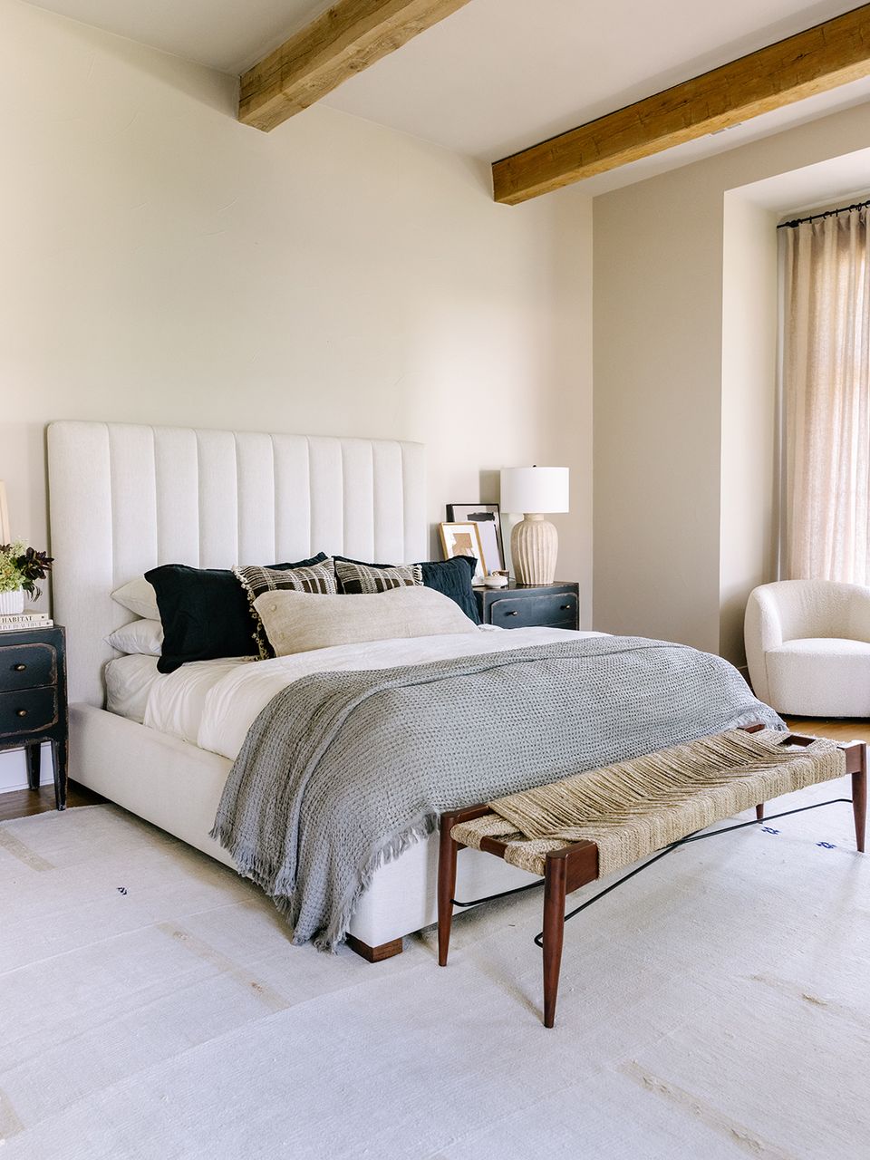 Transitional bedroom with exposed wooden beams, white bedding, and balanced neutral tones