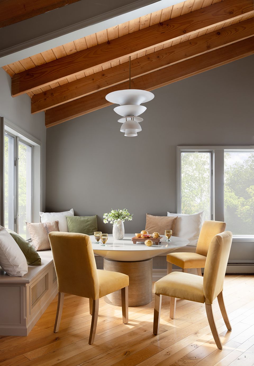 Mid-century dining nook with exposed wood beams, sage walls, and intentional spacing around round table
