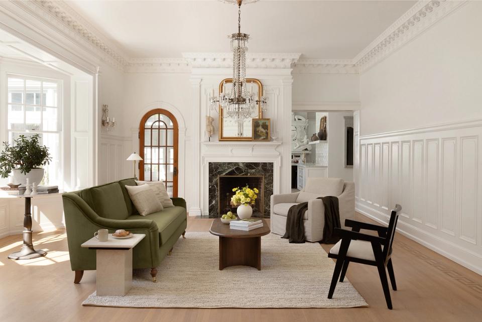 Transitional living room with sage green sofa, classic fireplace, and elegant architectural details