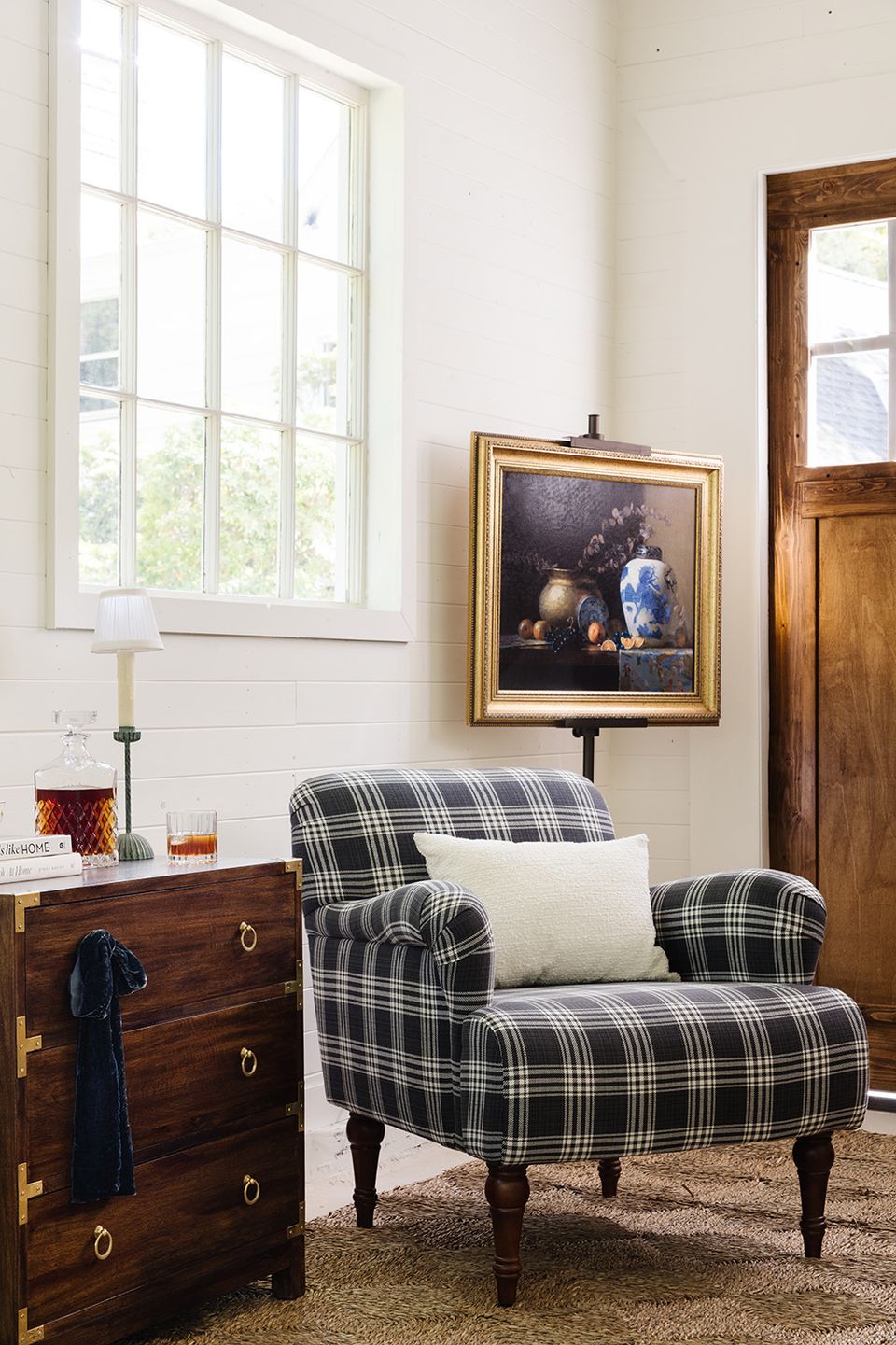 Transitional coastal nook with plaid armchair, natural light, and vintage nautical accents