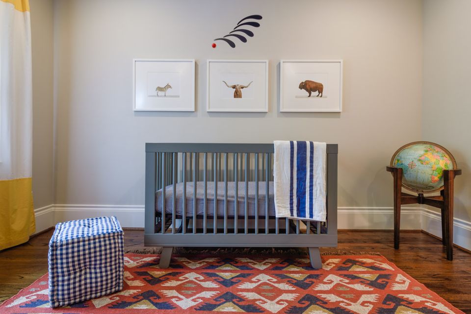 Southwestern nursery with geometric rust rug, gray crib, striped curtains, and Native American-inspired wall art