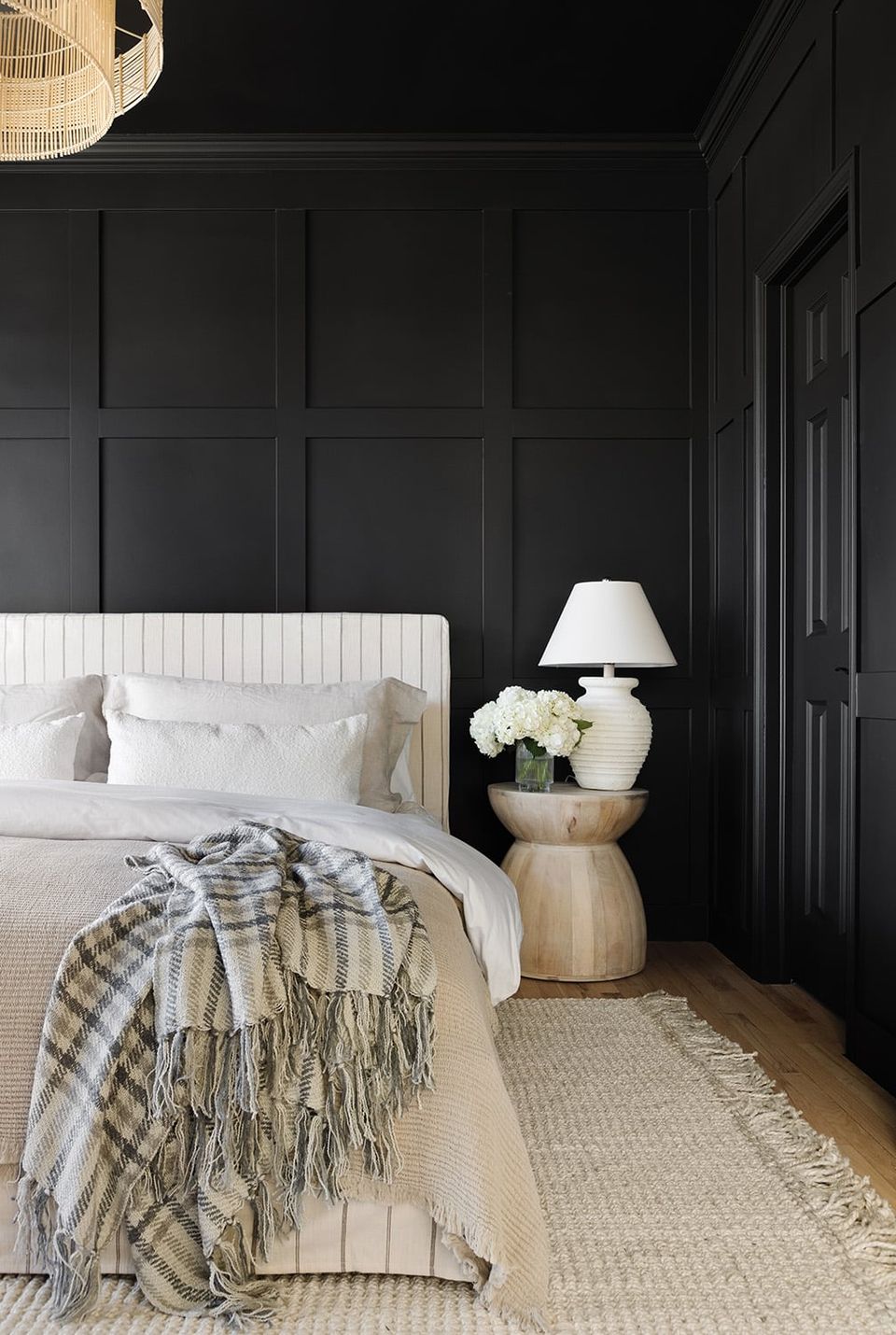 Contemporary bedroom with black raised panel wall moulding, white bedding, and neutral wood accents