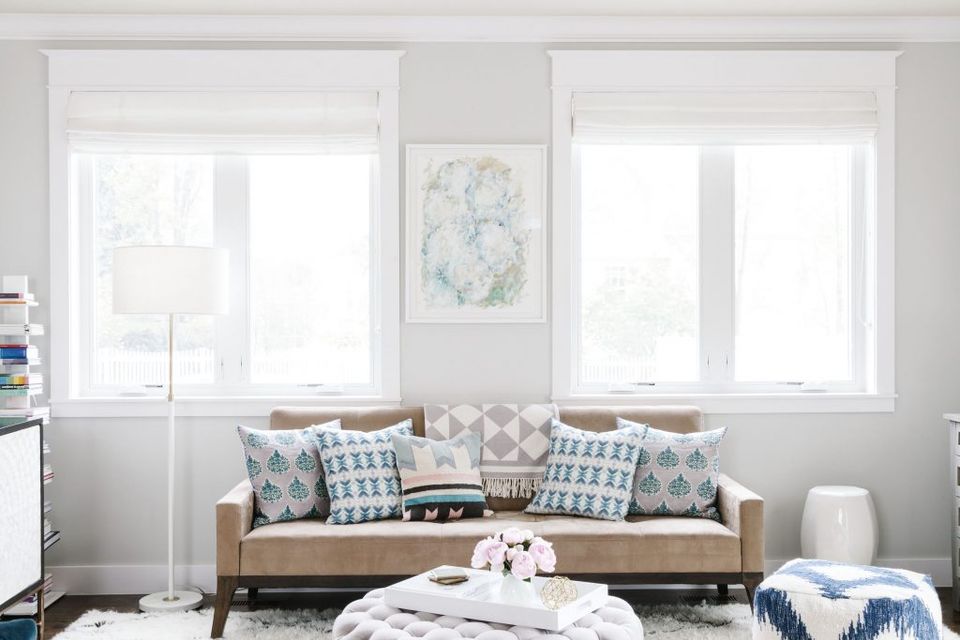 Scandinavian-inspired neutral space with crisp white roller shades and patterned throw pillows on tan sofa