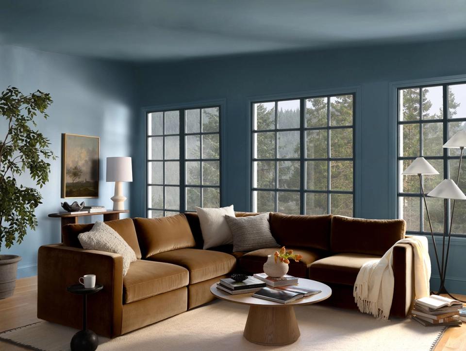 Contemporary living room with muted teal walls, cognac sectional, and warm ambient lighting