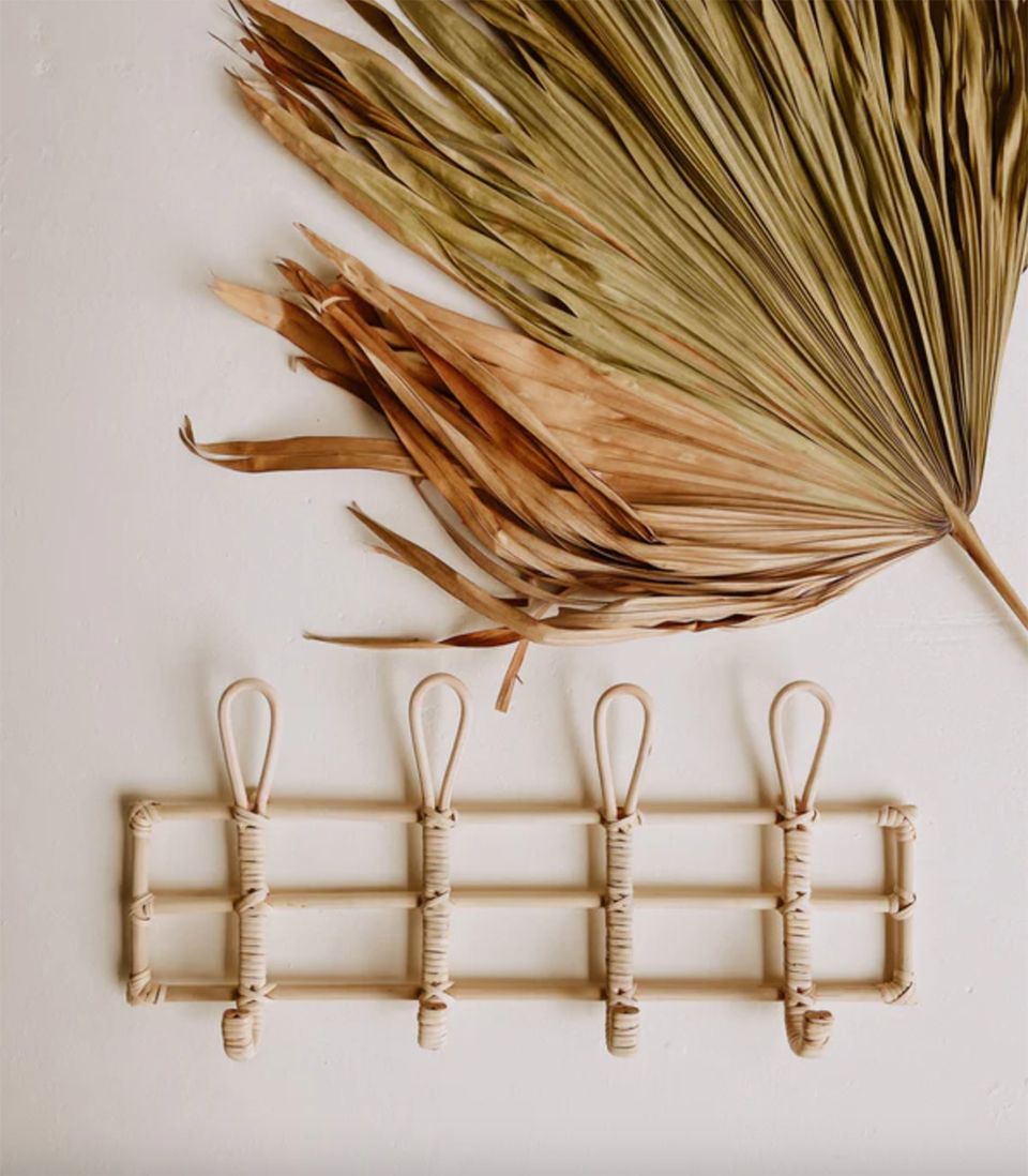 Minimalist wall organization with natural woven rattan hooks and dried palm leaves in earthy tones