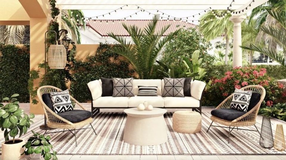 Tropical-inspired courtyard with black and white striped patterns, lush palms, and woven seating for bold boho style.