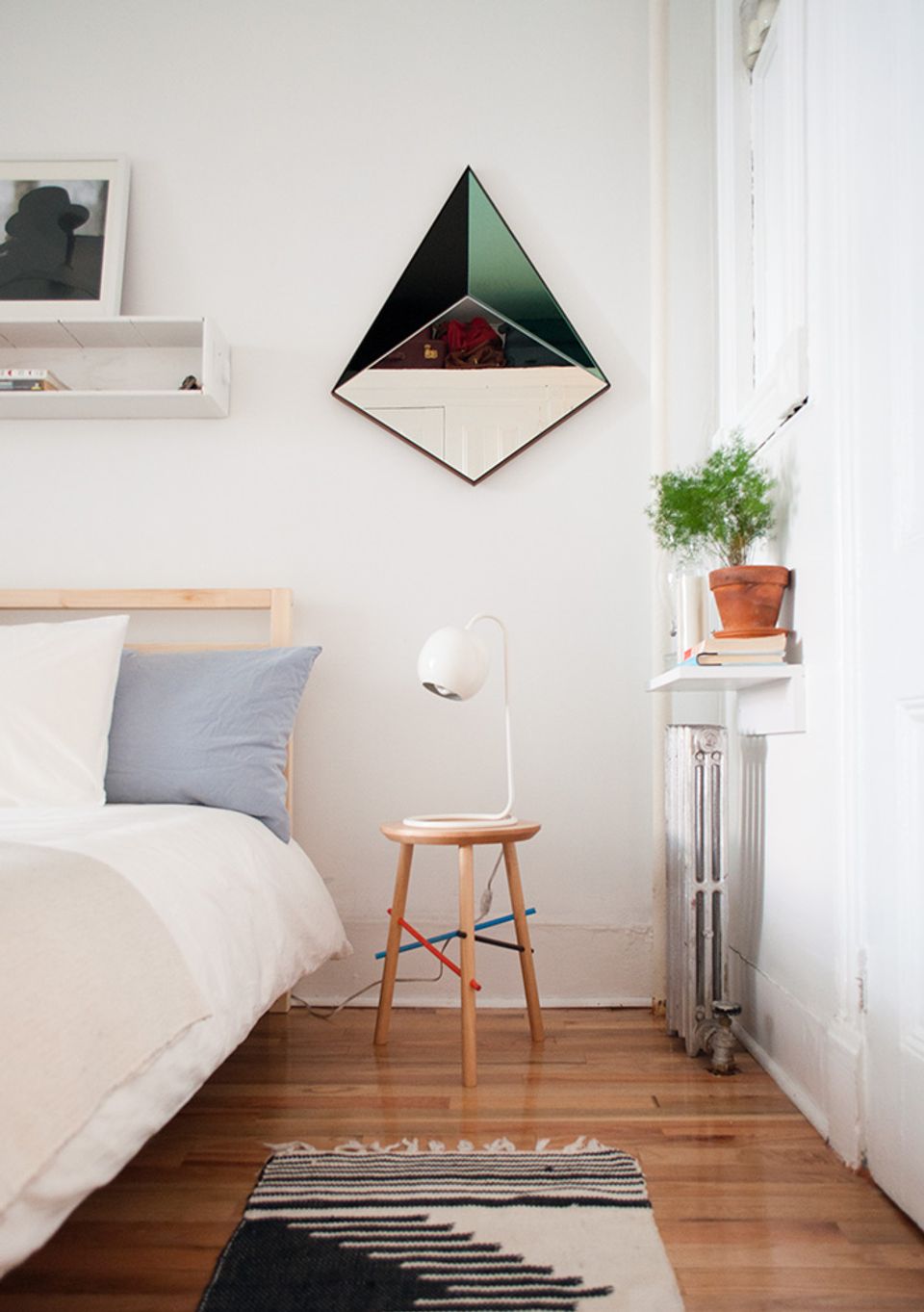 Scandinavian bedroom corner with minimalist geometric mirror and warm wood accents