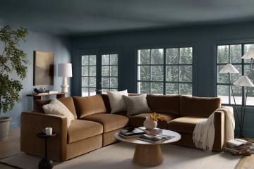 Modern living room with caramel leather sectional, teal walls, and abundant natural light from gridded windows