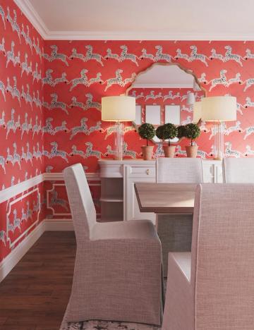 Playful coral wallpaper with whimsical pattern transforms compact home office with feminine charm