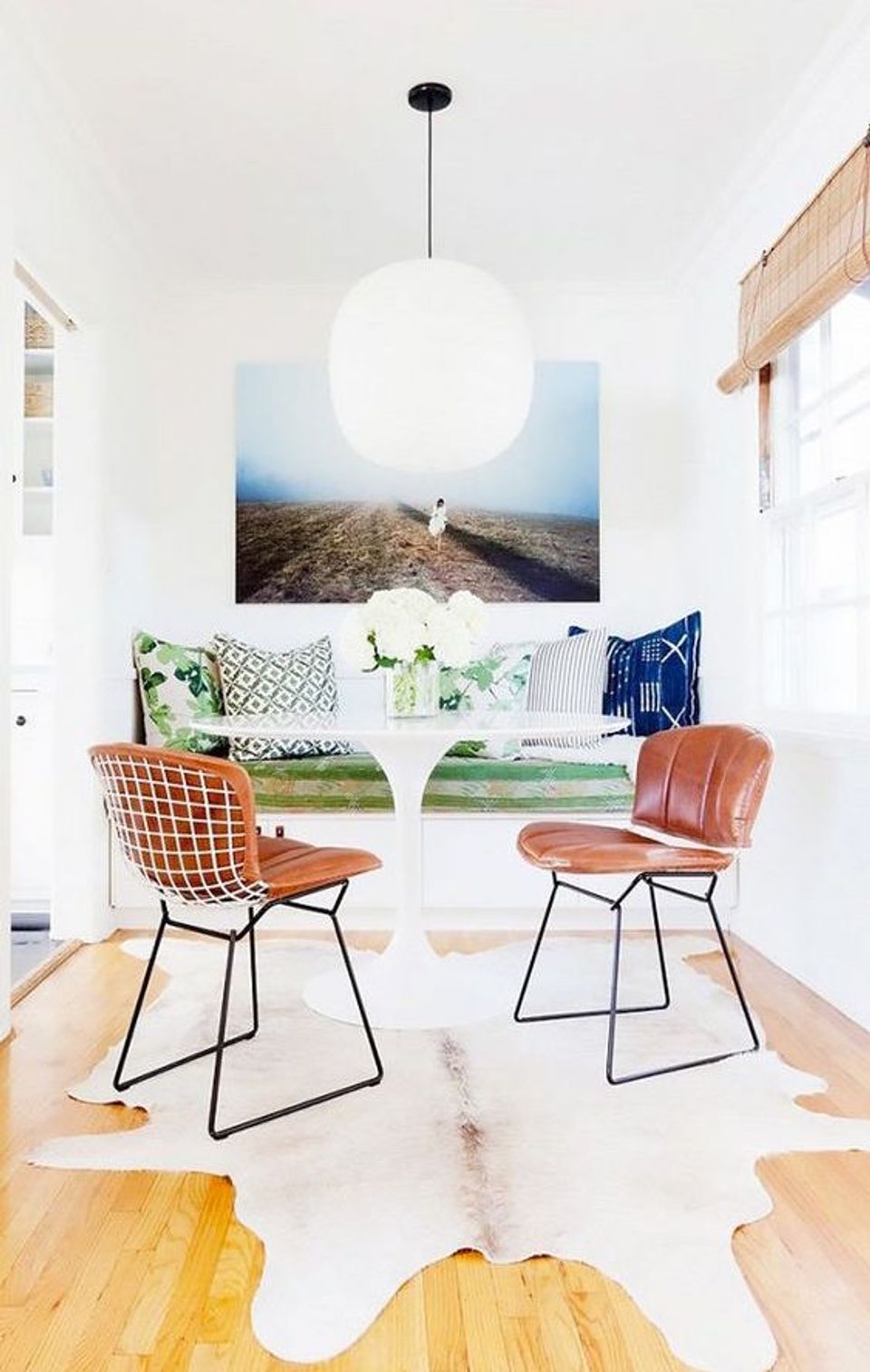 Bright minimalist lounge with cognac mid-century chairs, landscape artwork, and airy Scandinavian aesthetic