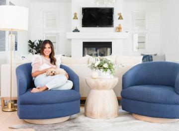 Modern living room with curved navy blue armchairs, white fireplace, and soft neutral accents creating a cozy, contemporary aesthetic.