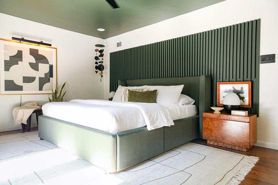 Modern bedroom with sage green vertical ribbed accent wall, white bedding, and warm wood nightstand