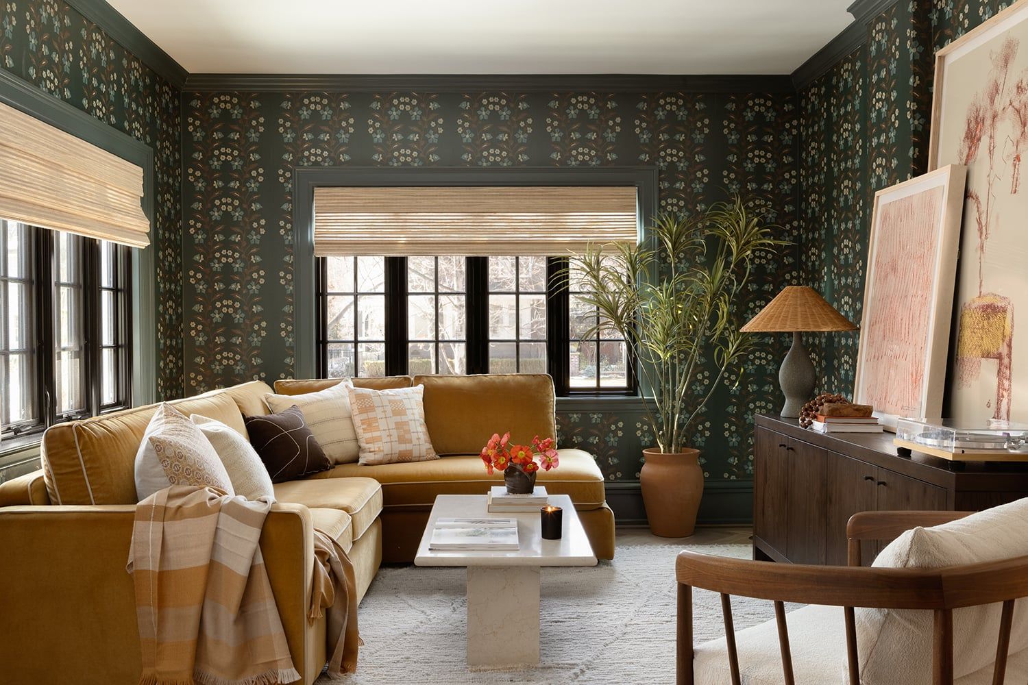 Modern traditional living room with forest green patterned wallpaper, golden mustard sofa, warm wood tones, and maximalist eclectic style