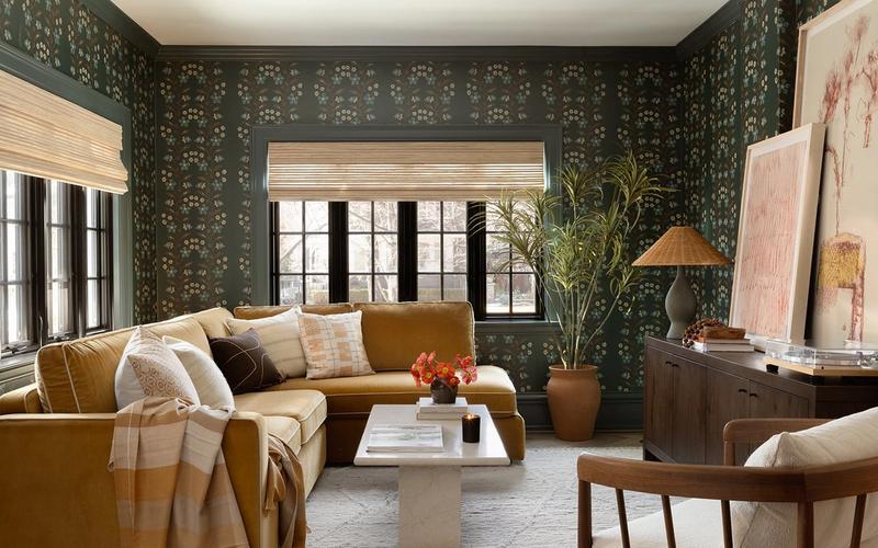 Modern traditional living room with forest green patterned wallpaper, golden mustard sofa, warm wood tones, and maximalist eclectic style