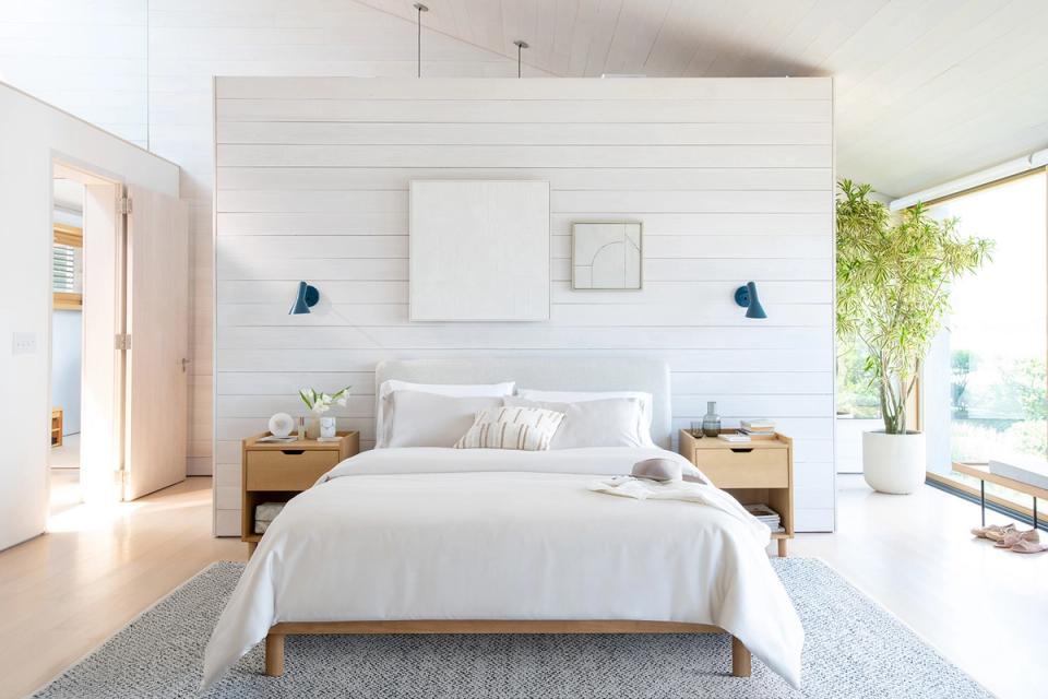 Scandinavian bedroom with white shiplap accent wall, natural wood frame, and serene white palette