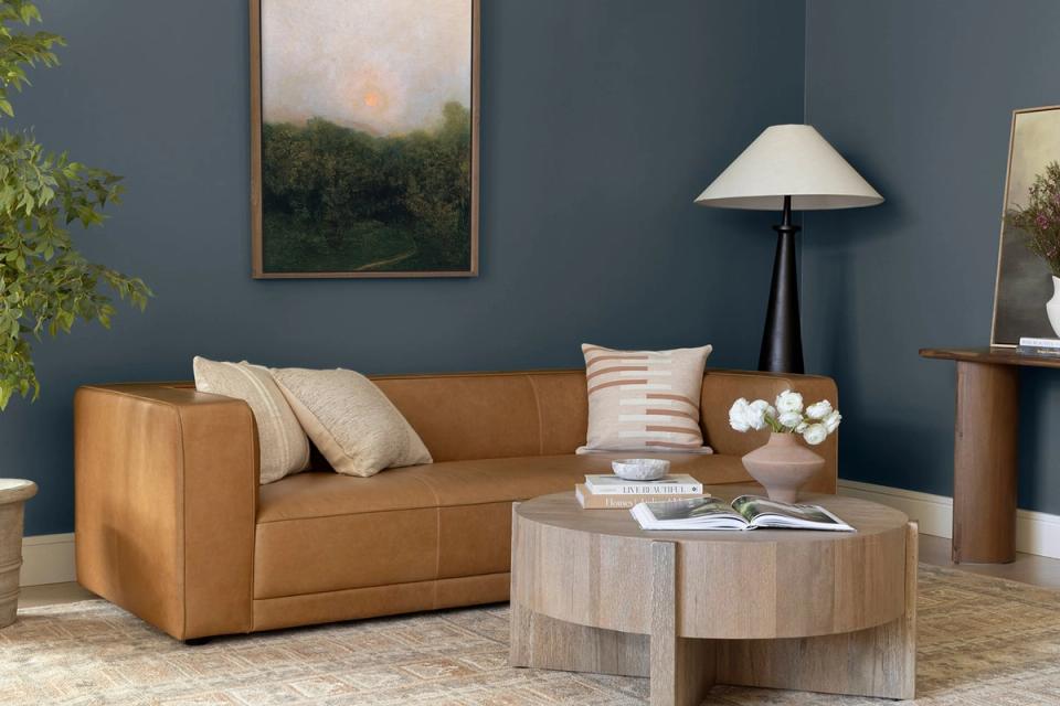 Contemporary space blending caramel leather sofa with slate blue walls and natural wood accents