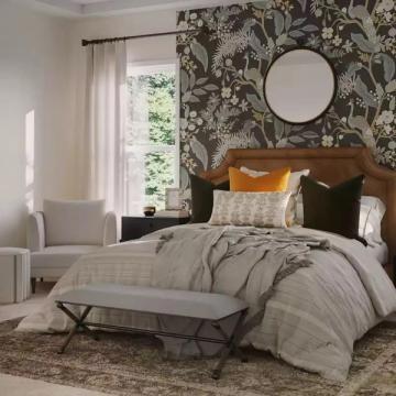 Botanical bedroom retreat pairing dark floral wallpaper accent wall with warm wood bed, neutral bedding, and soft natural light.