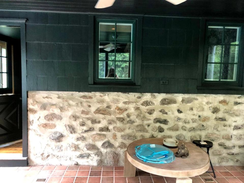 Rustic mudroom with dark teal walls, natural stone lower half, and terra cotta flooring