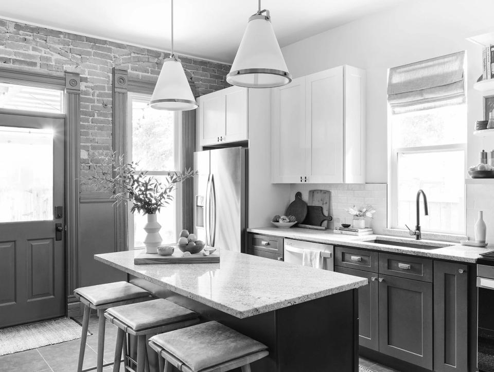 Modern two-tone kitchen with black lower cabinets, white uppers, marble countertop, and industrial pendant lighting creating a contemporary contrast.