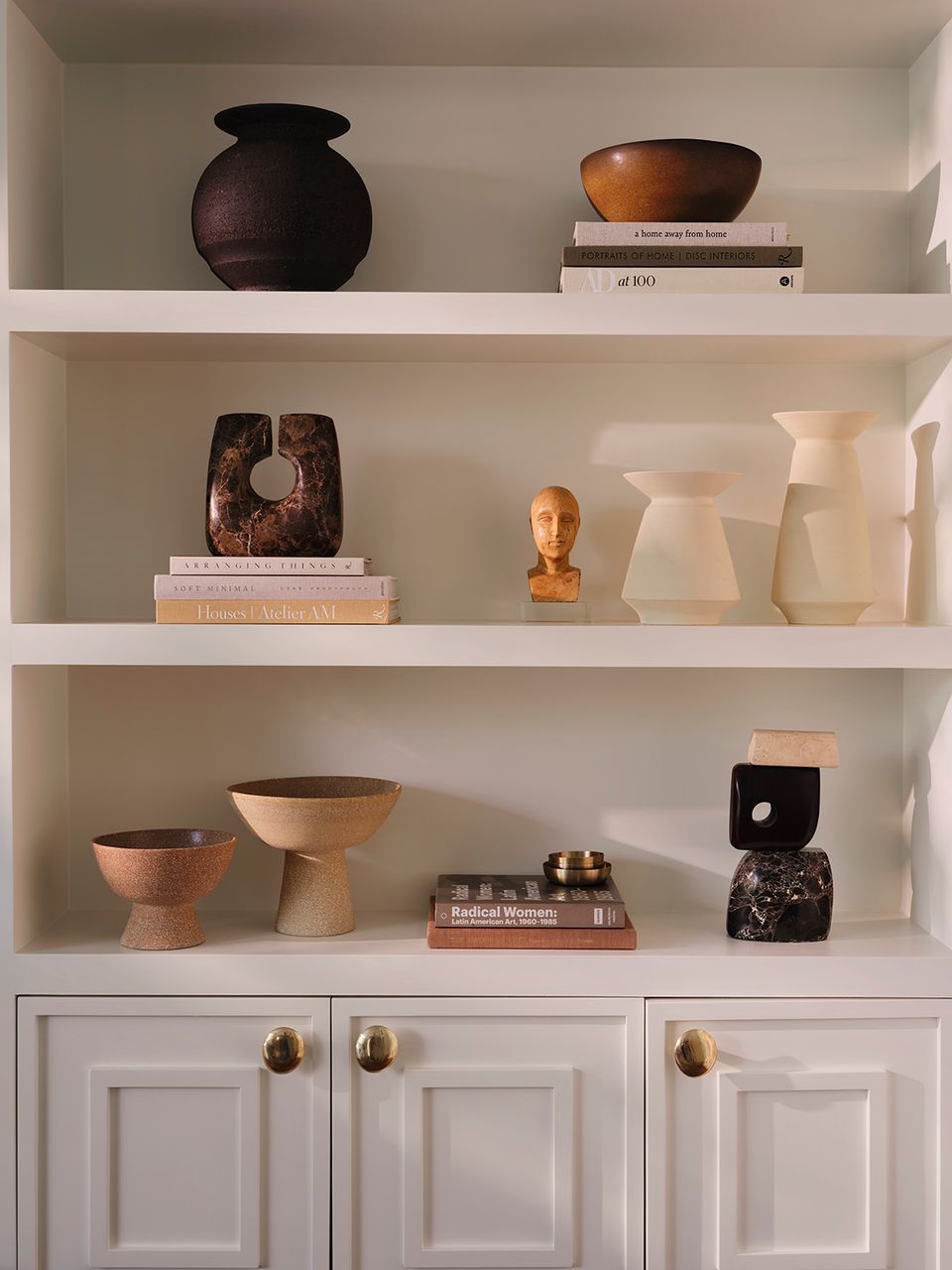 Curated shelving display mixing sculptural ceramics, warm wood tones, and earthy minimalist styling