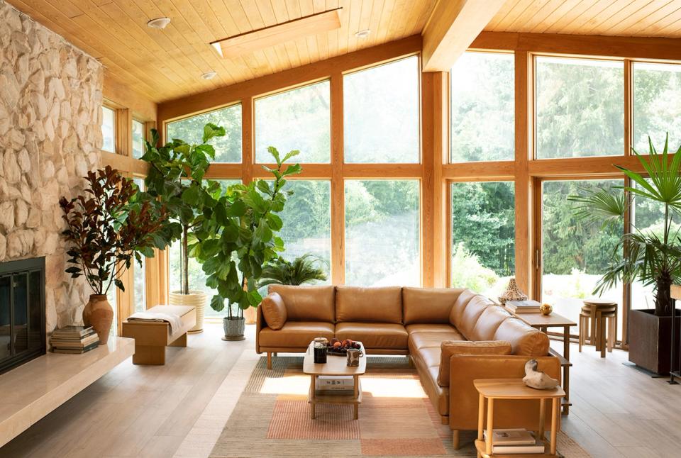 Modern warm-toned living room with fireplace, caramel leather sofa, and abundant natural light