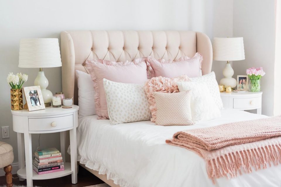 Soft feminine bedroom with blush pink headboard, white bedding, and pale rose textured pillows
