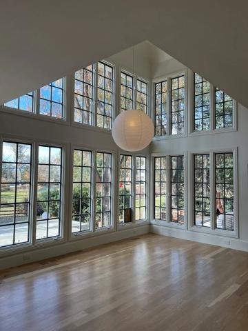 Contemporary minimalist double-height space with floor-to-ceiling gridded windows and sculptural pendant lighting