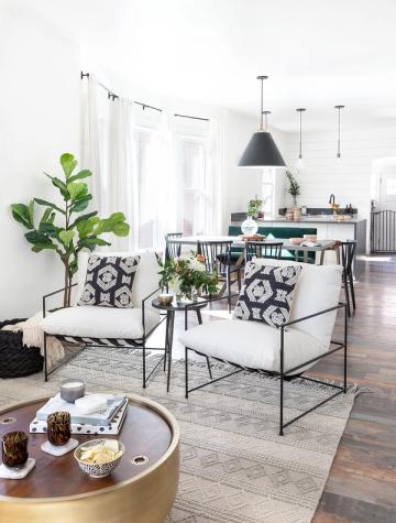 Mid-century modern living and dining combo with graphic black-and-white accents, fresh greenery, and geometric pendant lighting in neutral tones.