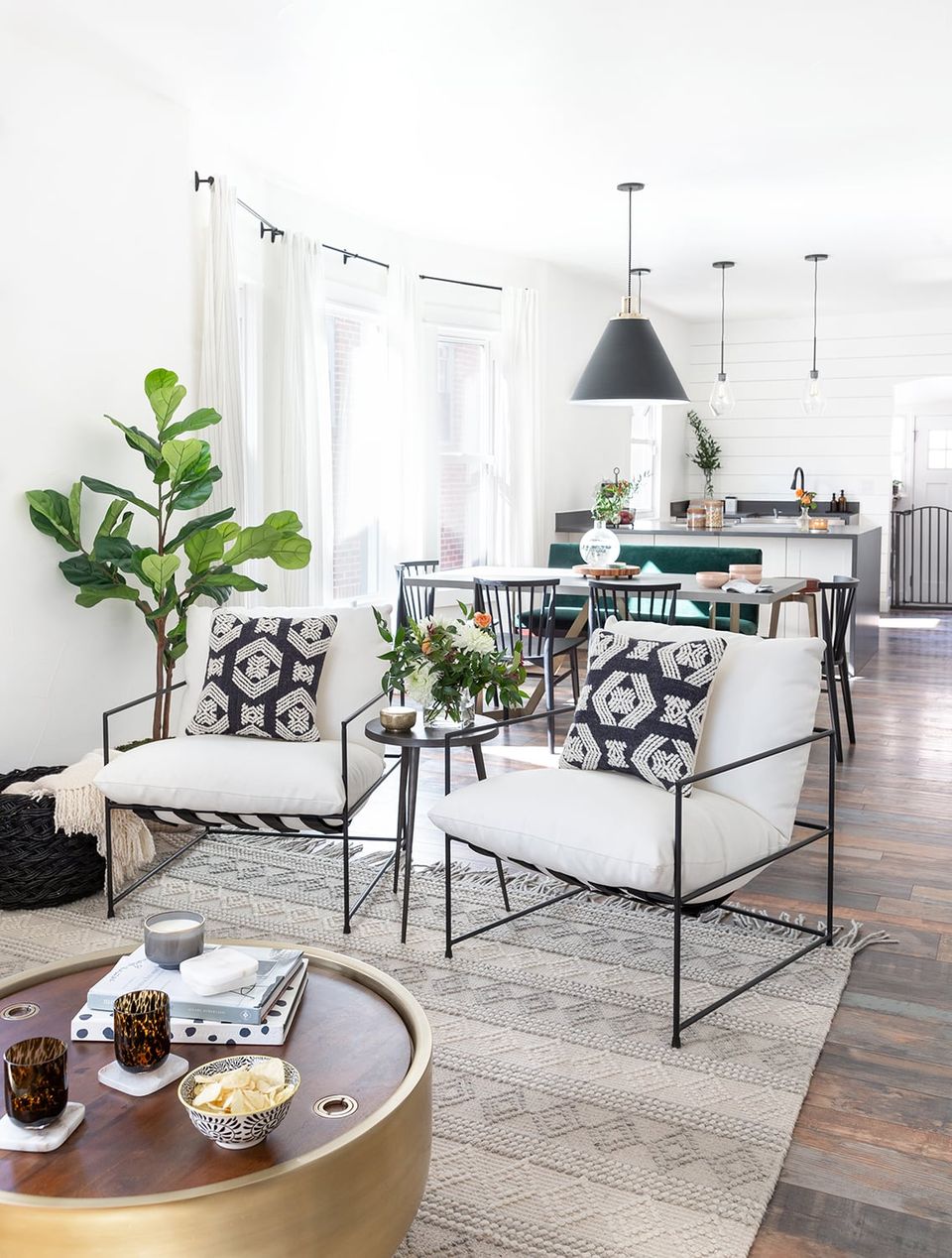 Mid-century modern living and dining combo with graphic black-and-white accents, fresh greenery, and geometric pendant lighting in neutral tones.