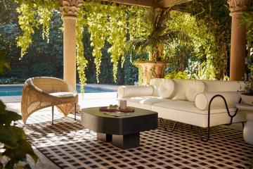 Mid-century modern patio with cream sofa, rattan chair, geometric rug, pergola canopy