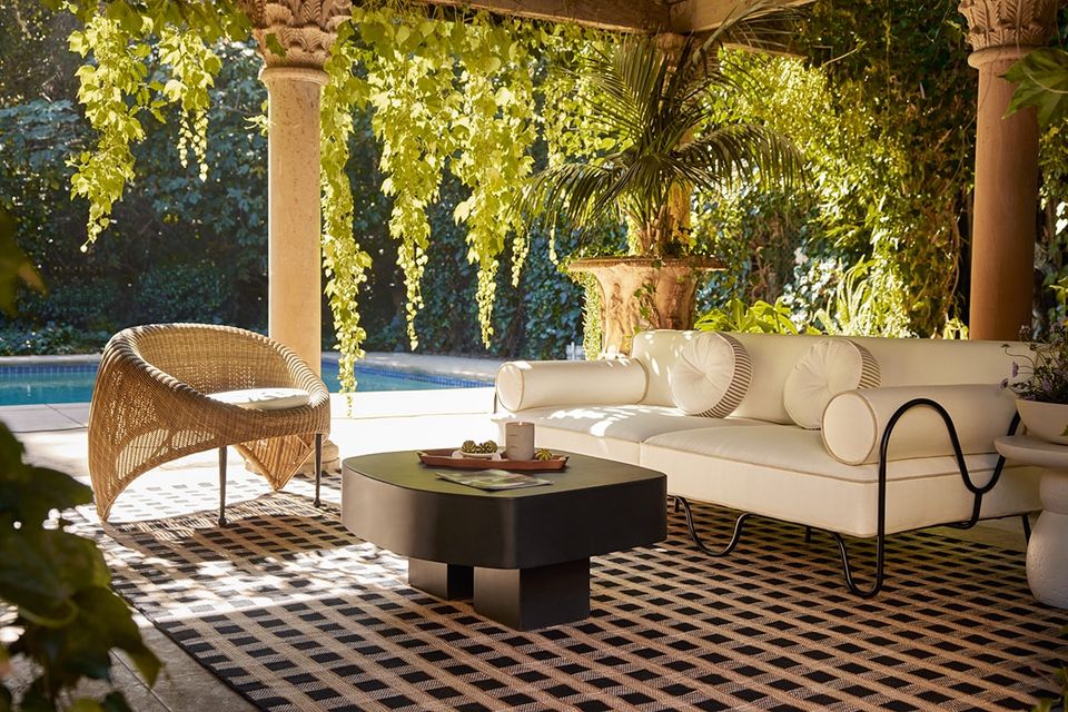 Mid-century modern patio with cream sofa, rattan chair, geometric rug, pergola canopy