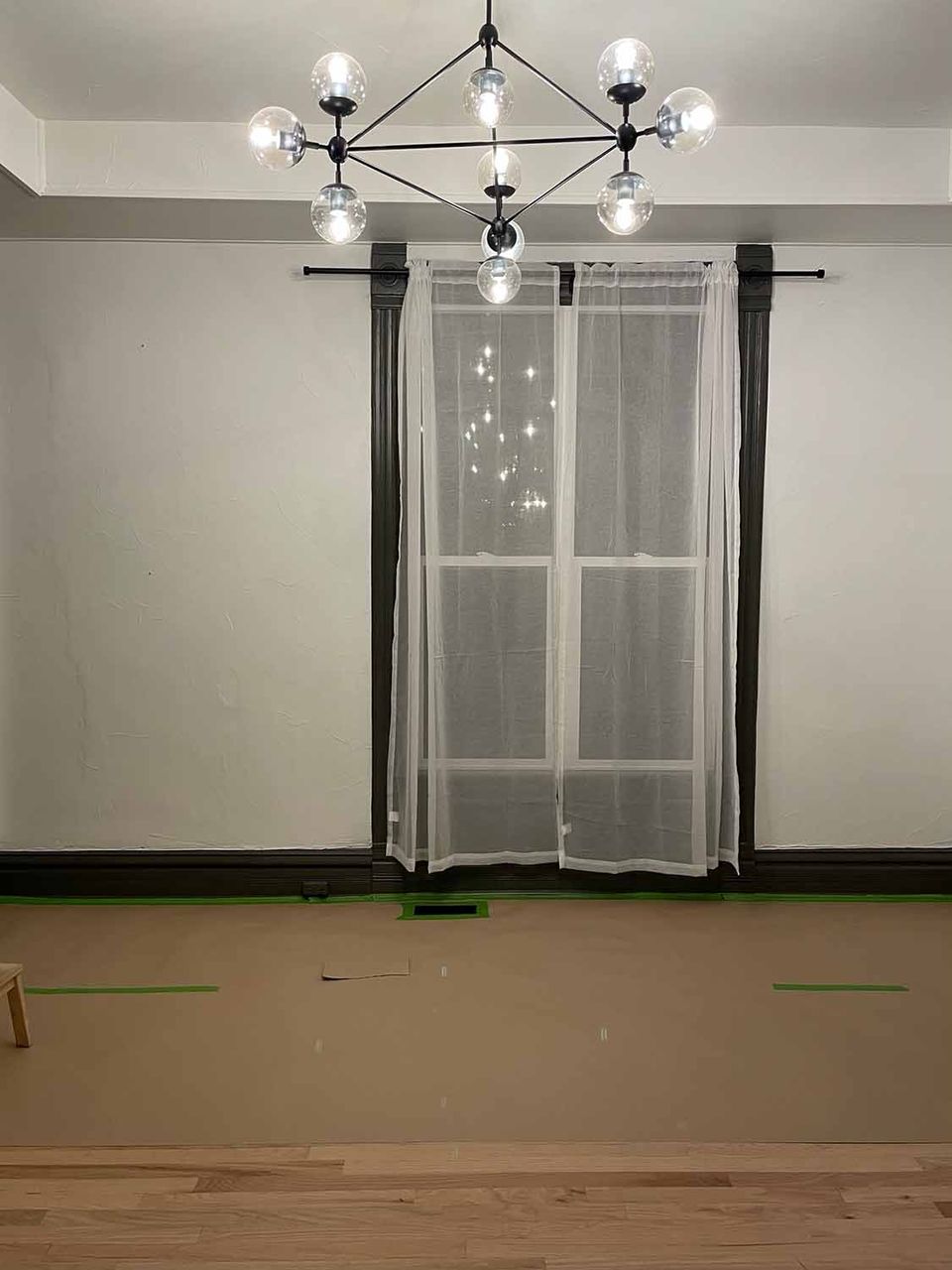 Minimalist room with modern black chandelier, sheer curtains, and clean architectural lines