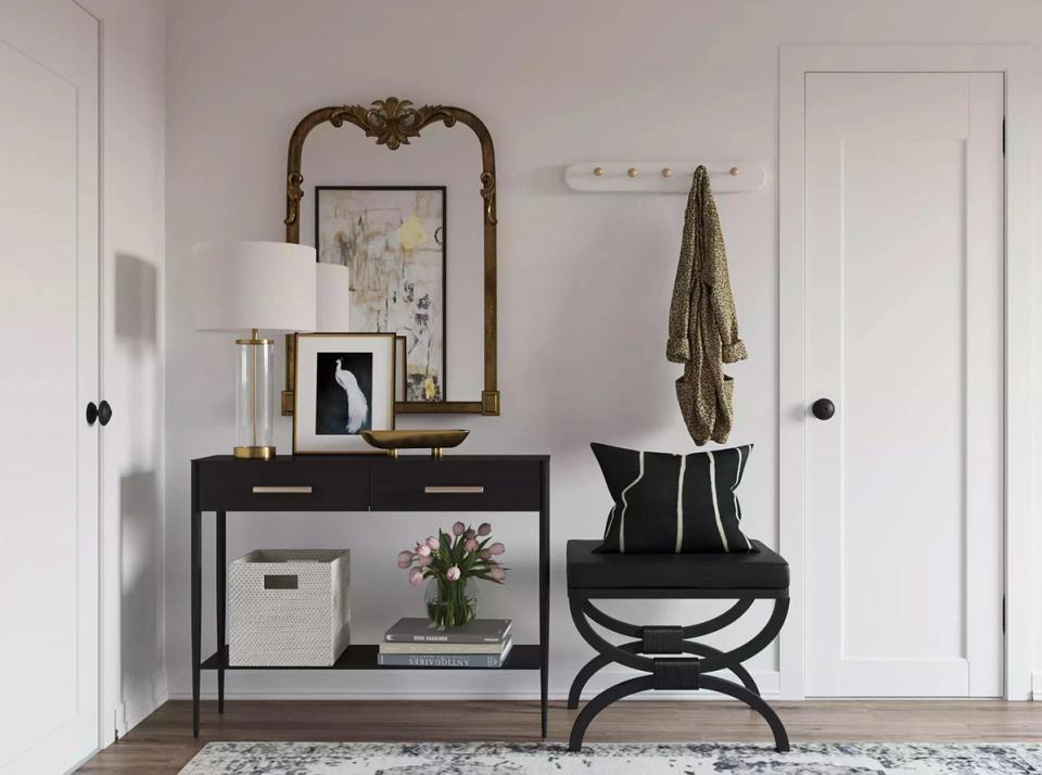 Modern minimalist entryway with black console, curved chair, and understated brass lighting