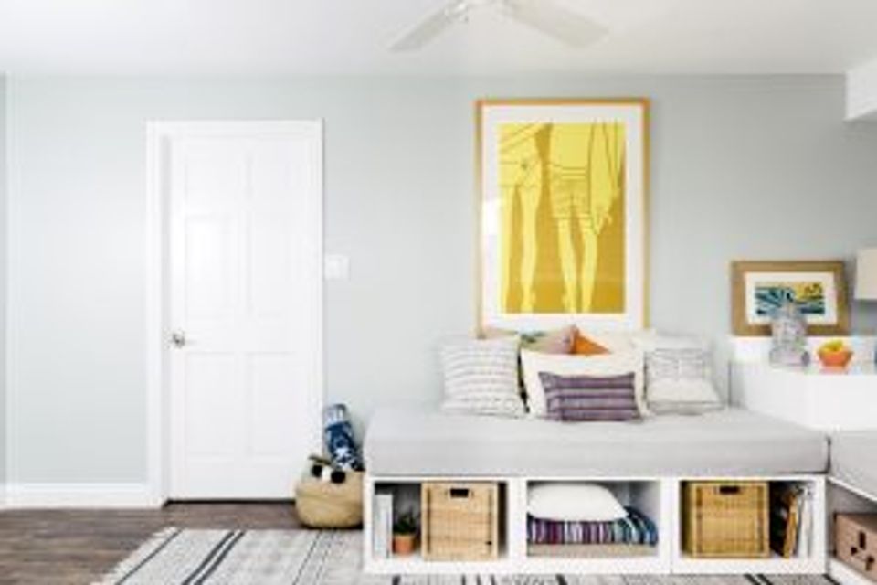Bright modern bedroom featuring white walls, mustard artwork, woven storage, and serene atmosphere