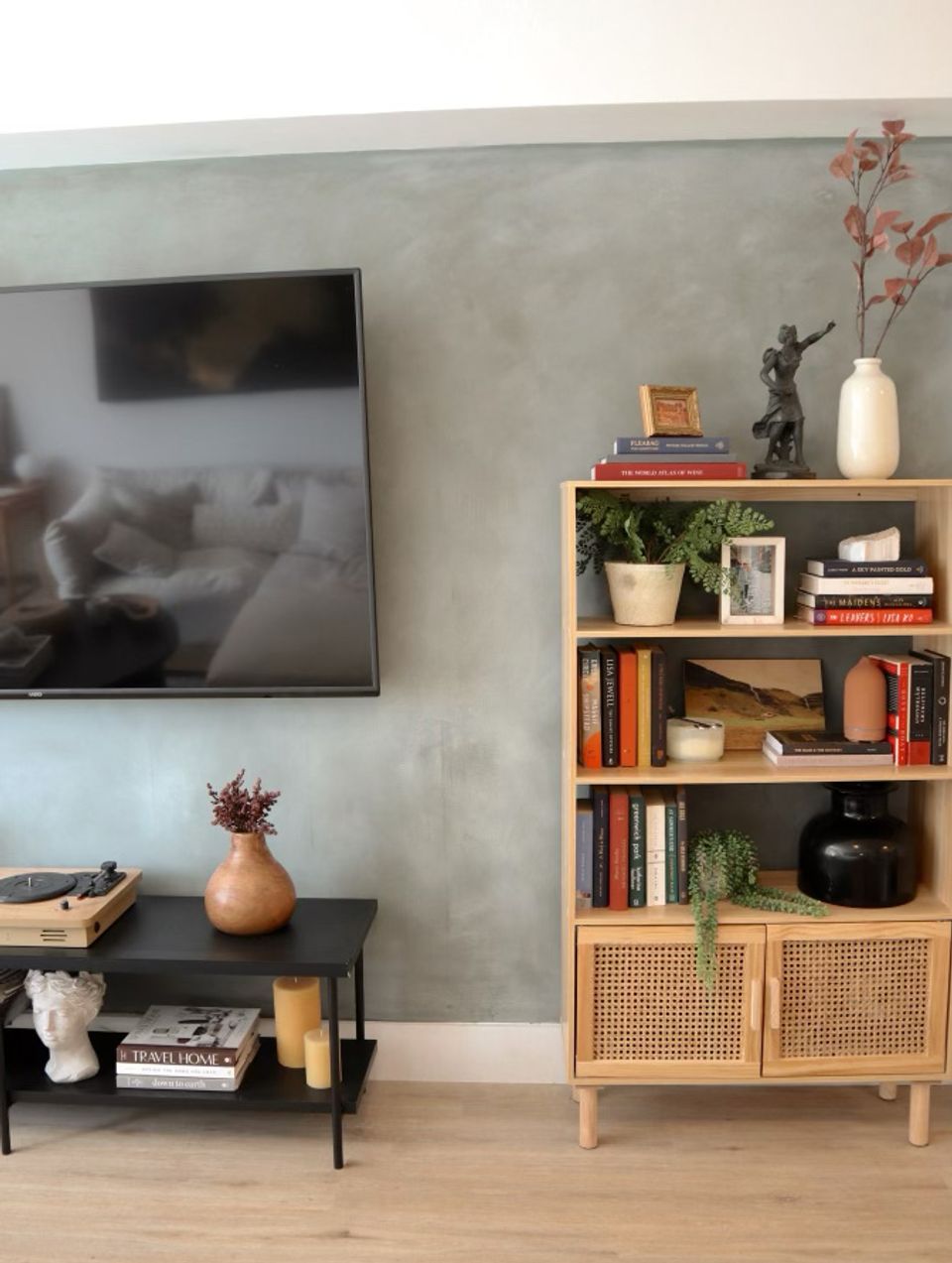 Contemporary media wall with muted green limewash finish, light wood shelving, and minimalist décor.