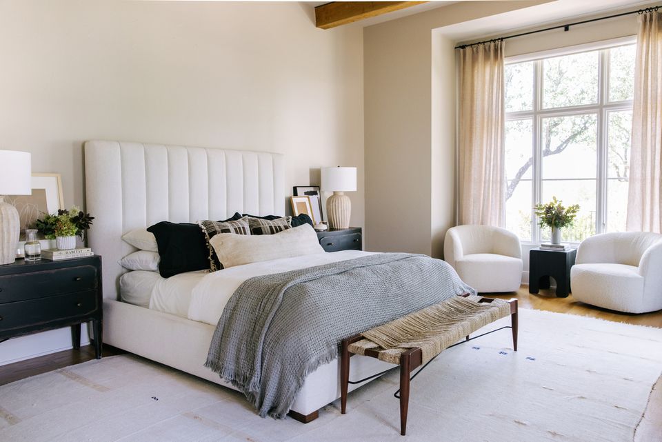Airy modern bedroom with vertical-ribbed white headboard, gray linens, exposed beams, and natural warmth