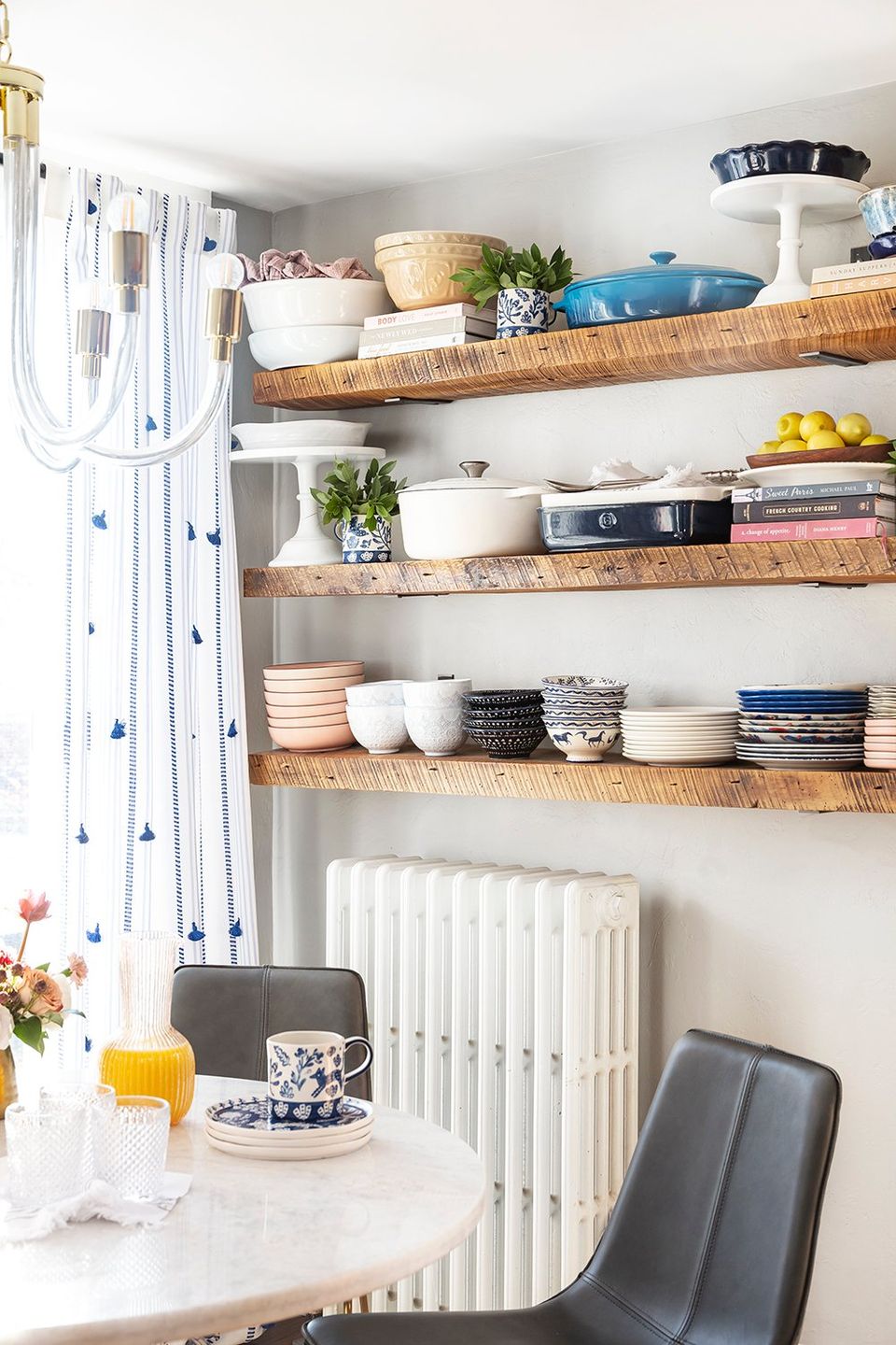 Bright Scandinavian kitchen with cream walls, wooden floating shelves, and blue striped curtains