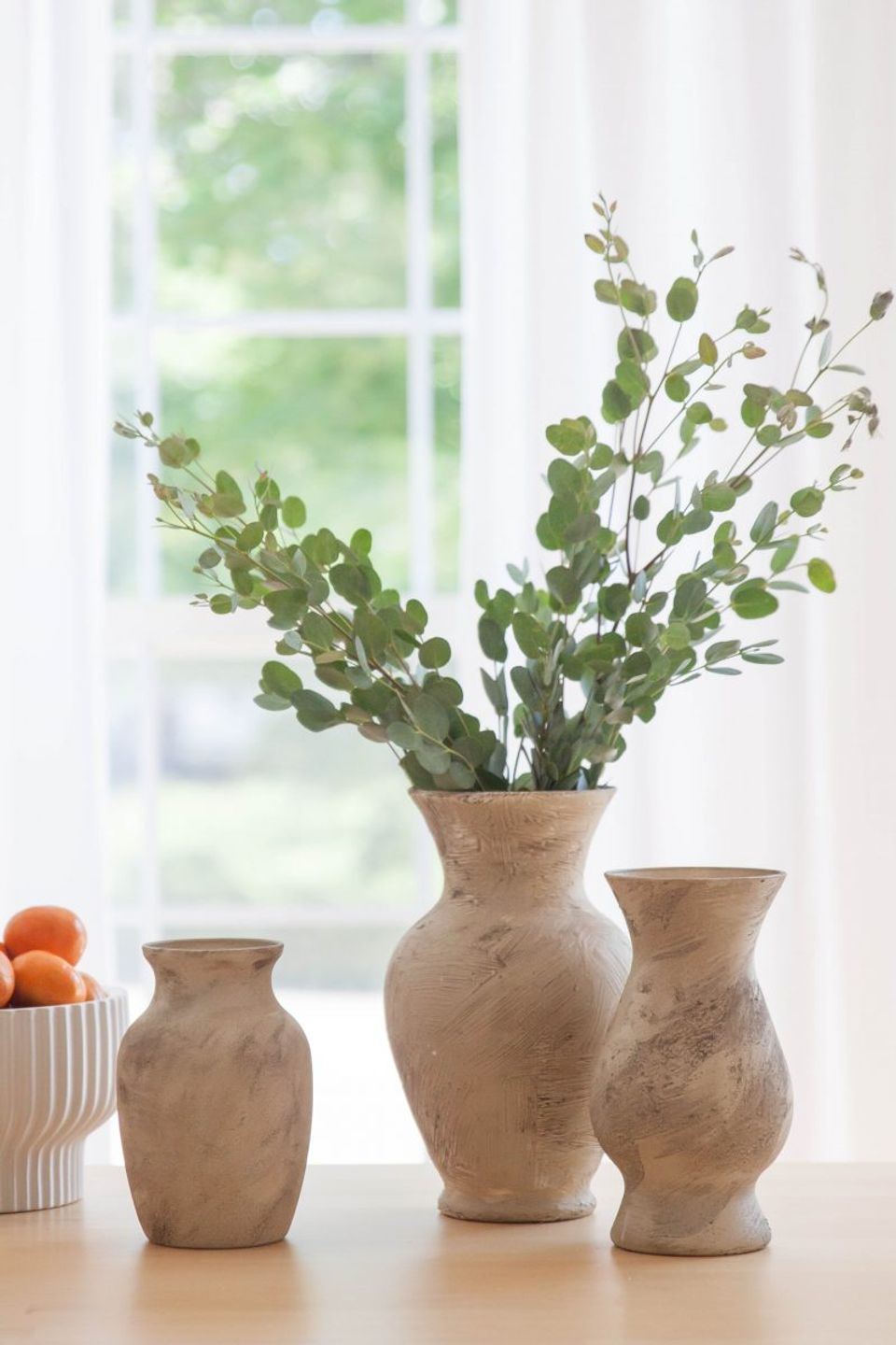 Serene windowsill with textured terracotta vases, dried botanicals, and diffused natural light