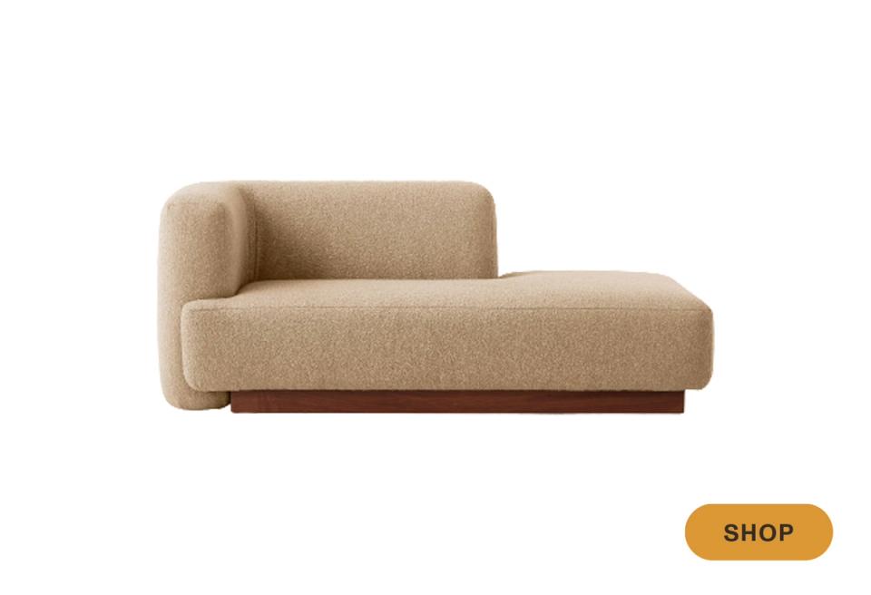 Modern curved daybed with rounded armrests in warm beige linen and dark wood base.