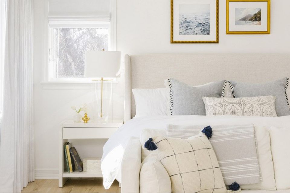 Serene coastal bedroom with cream palette, brass-framed art, and relaxed nautical accents