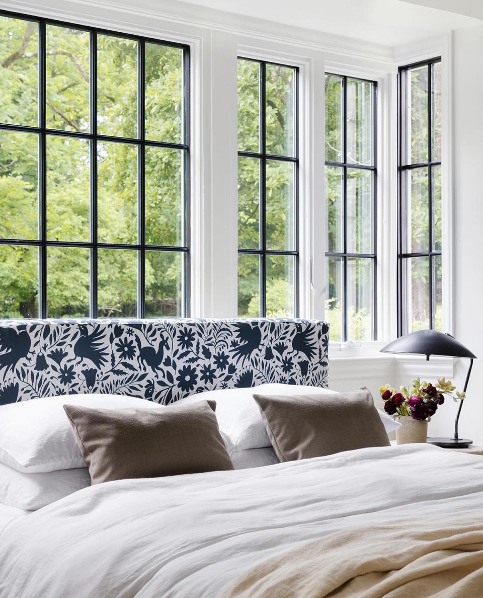 Contemporary bedroom with black-framed windows, bold patterned headboard, and neutral bedding