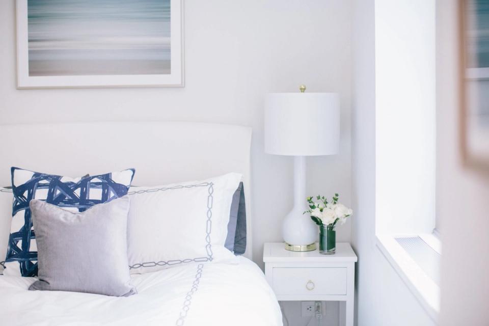 Serene coastal bedroom with crisp white bedding, navy blue accents, and minimalist nightstand styling