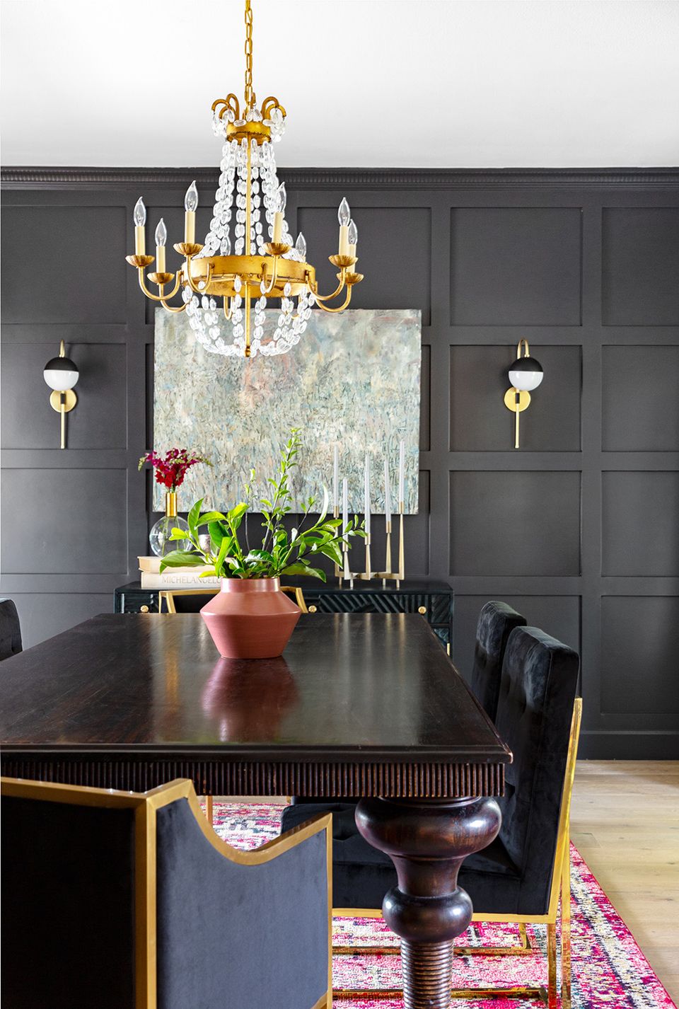 Dramatic dining room with bold charcoal panel moulding, gold chandelier, and moody glamorous aesthetic
