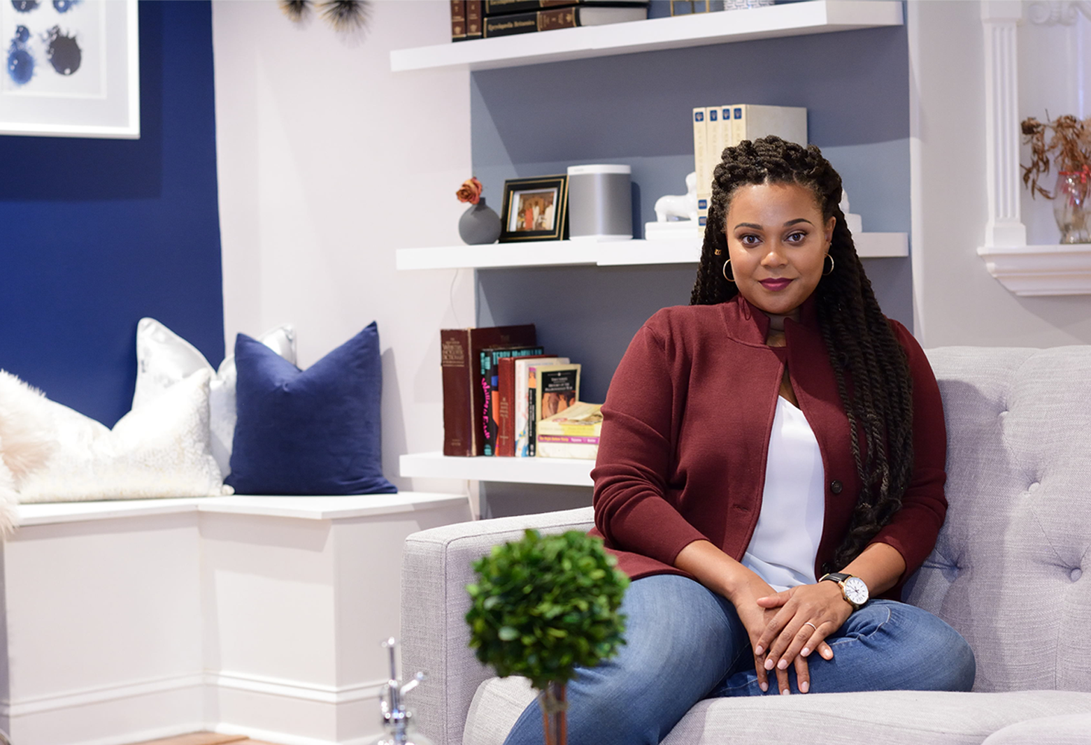 Modern living room with bold navy accent wall, white built-in shelving, and jewel-tone burgundy accents creating sophisticated, curated aesthetic.
