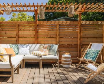 Warm mid-century modern deck with natural wood pergola, neutral seating, and earthy patterned pillows