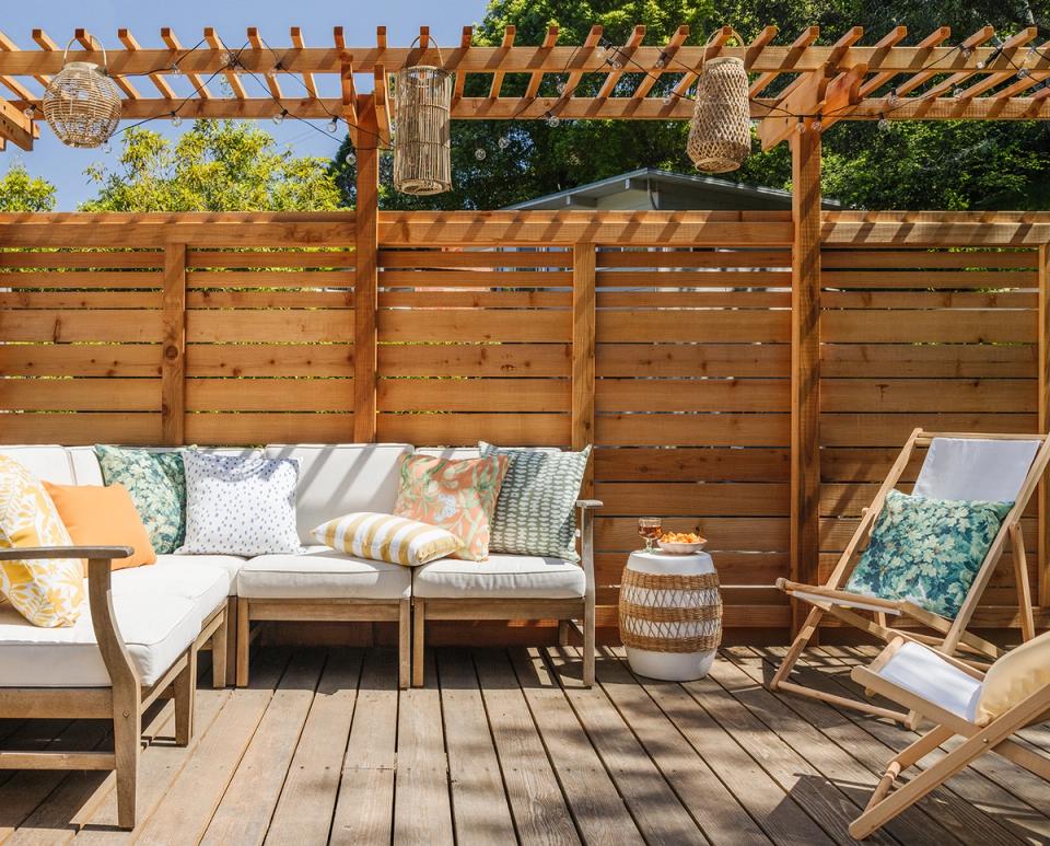 Warm mid-century modern deck with natural wood pergola, neutral seating, and earthy patterned pillows
