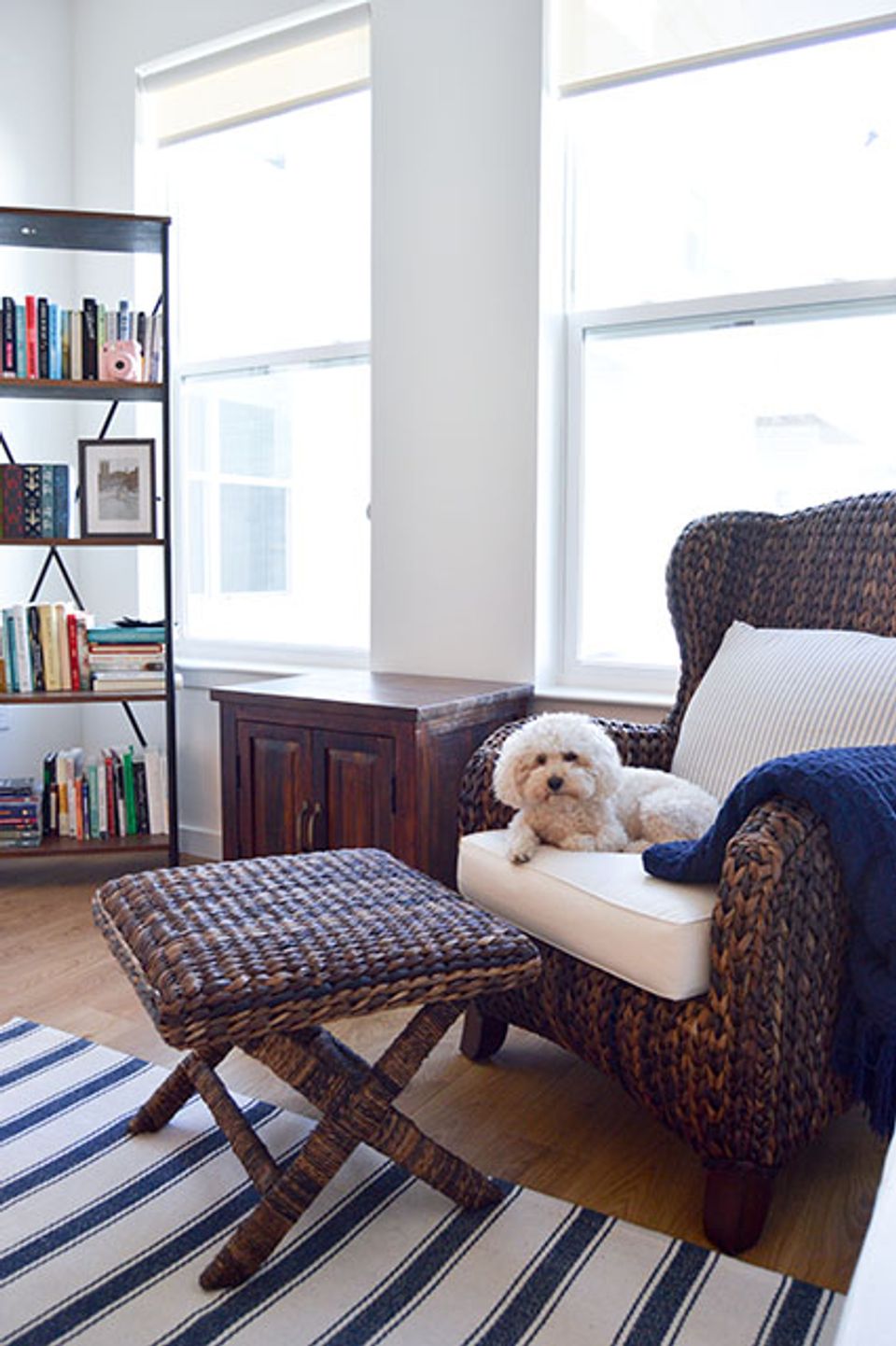 Cozy reading nook with woven chair, striped rug, navy pillows, and built-in shelving