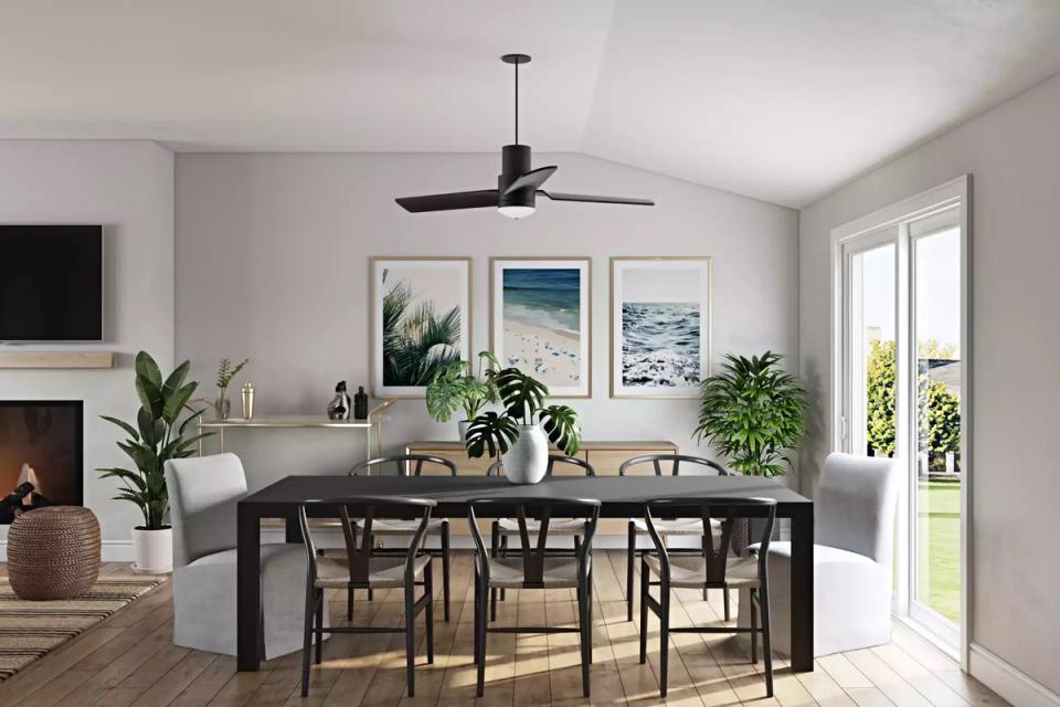 Serene coastal dining with black table, light upholstered chairs, ocean art, and soft blue walls