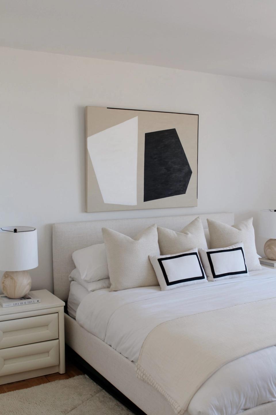 Modern bedroom featuring geometric wall art and layered neutral textures throughout